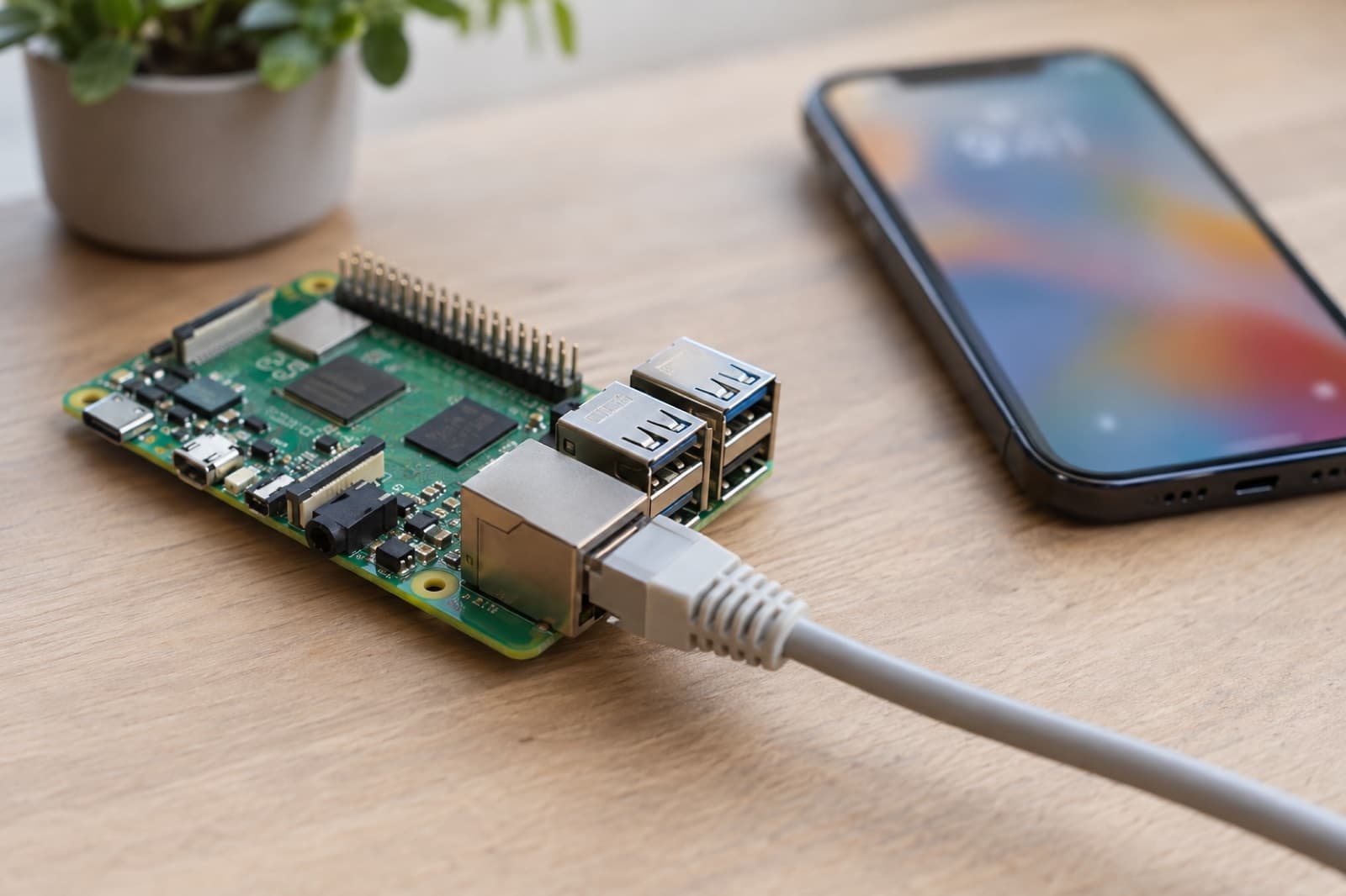 A Raspberry Pi 5 on a desk with an Ethernet cable, an iPhone beside it